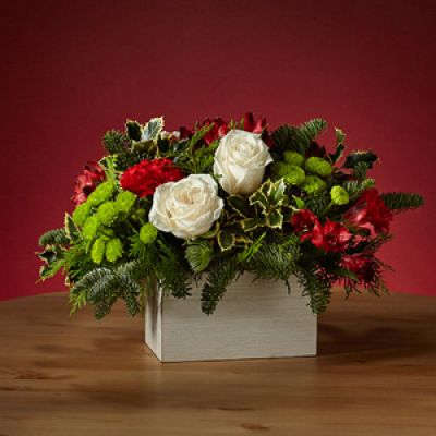 Dress the tablescape in winter wanderlust with our Snow Ball Bouquet and add an air of sophistication with the elegance of white roses. The holly lays over a white wooden box, perfect for a tasteful holiday gathering.