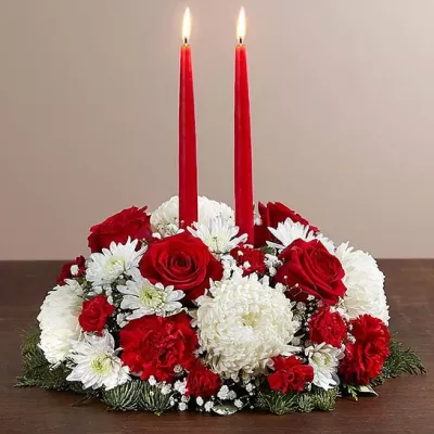 Deck the halls with our festive Christmas centerpiece. This traditional arrangement is filled with red & white blooms, and finished off with a red taper candle or two, casting a warm glow over holiday gatherings, while adding seasonal beauty to your home.